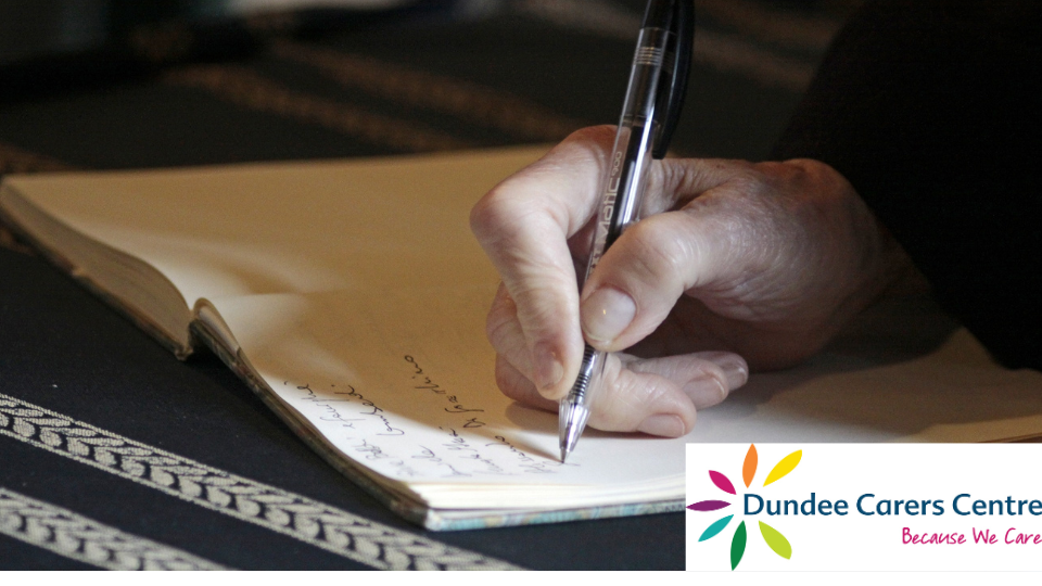 Clost up view of a hand writing in a notebook. Dundee Carers Centre logo is on the bottom right.