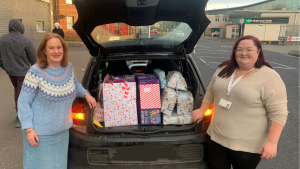 DCC staff standing by a boot of a car that is filled with Xmas presents. 