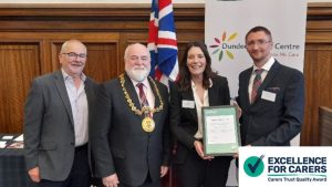 Group photo of Alan Baird, The Lord Provost, Becky from Carers Trust and Neil Campbell, CEO of Dundee Carers Centre posing with the Carers for Excellence certificate that was awarded to Dundee Carers Centre.