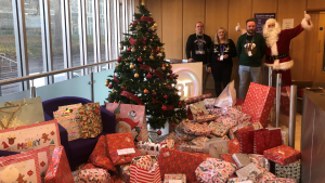 Picture of Santa and staff from BT Dundee posing alongside presents donated by BT staff for young carers in Dundee.
